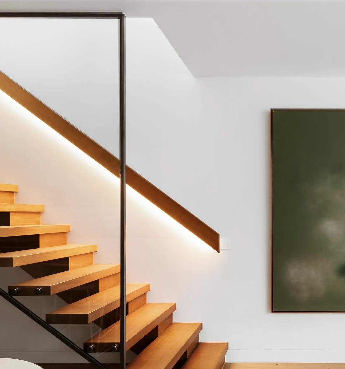 Custom timber staircase with glass balustrade and integrated lighting in Carlton North